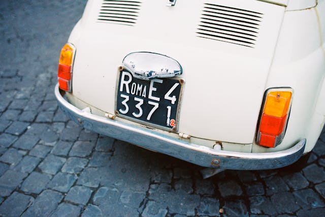 Vintage white Fiat car with visible number plate on rear bumper