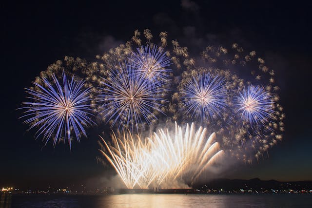 Fireworks illuminate the night sky over water, creating a mesmerizing display. Compliant with Arkansas fireworks laws